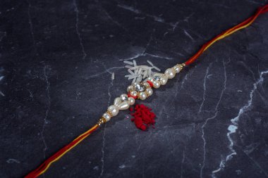 Raksha Bandhan: Taş zemin üzerinde pirinç taneleri ve kumkum bulunan Rakhi, Kardeşler ve Kardeşler arasındaki aşkın sembolü olan geleneksel Hint bilekliği.