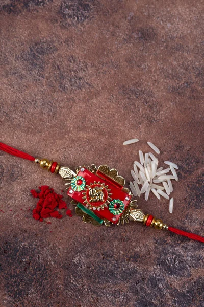 Raksha Bandhan: Rakhi with rice grains and kumkum on stone background, Традиційний індійський зап'ясток гурт, який є символом любові між братами і сестрами. — стокове фото
