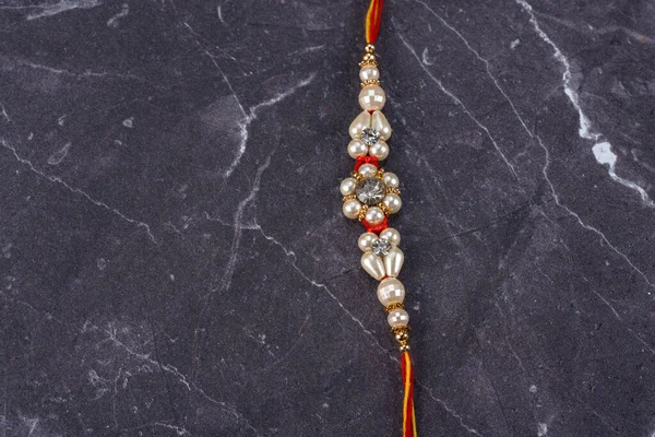 Raksha Bandhan: Rakhi con granos de arroz y kumkum sobre fondo de piedra, Muñequera tradicional india que es un símbolo de amor entre hermanos y hermanas . — Foto de Stock