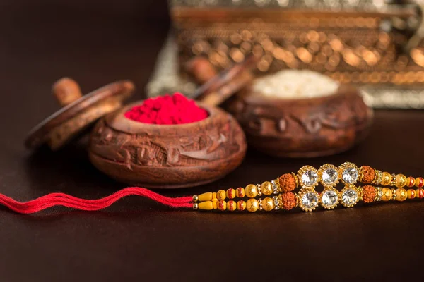 Festivalul indian: Raksha Bandhan fundal cu un elegant Rakhi, cereale de orez și Kumkum. O trupă tradițională indiană de încheietură a mâinii, care este un simbol al iubirii dintre frați și surori . — Fotografie, imagine de stoc