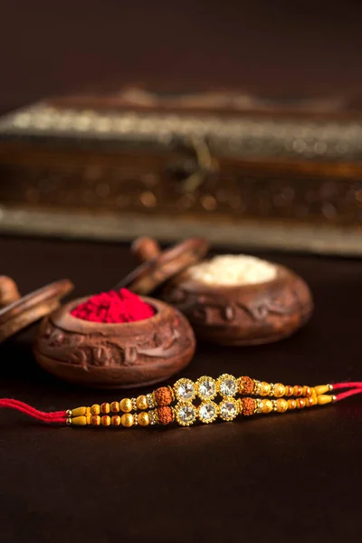 Festivalul indian: Raksha Bandhan fundal cu un elegant Rakhi, cereale de orez și Kumkum. O trupă tradițională indiană de încheietură a mâinii, care este un simbol al iubirii dintre frați și surori . — Fotografie, imagine de stoc