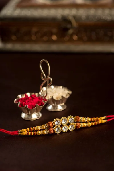 Indiska festival: Raksha Bandhan bakgrund med en elegant Rakhi, Rice Grains och Kumkum. Ett traditionellt indiskt armband som är en symbol för kärlek mellan bröder och systrar. — Stockfoto