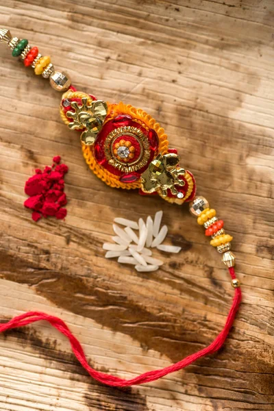 Indiska festival: Raksha Bandhan bakgrund med en elegant Rakhi, Rice Grains och Kumkum. Ett traditionellt indiskt armband som är en symbol för kärlek mellan bröder och systrar. — Stockfoto