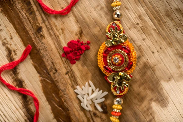 Indiska festival: Raksha Bandhan bakgrund med en elegant Rakhi, Rice Grains och Kumkum. Ett traditionellt indiskt armband som är en symbol för kärlek mellan bröder och systrar. — Stockfoto