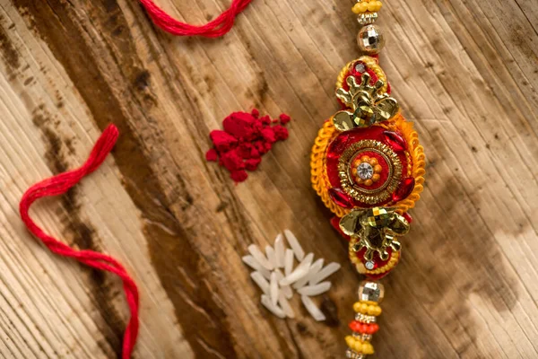 Indiska festival: Raksha Bandhan bakgrund med en elegant Rakhi, Rice Grains och Kumkum. Ett traditionellt indiskt armband som är en symbol för kärlek mellan bröder och systrar. — Stockfoto