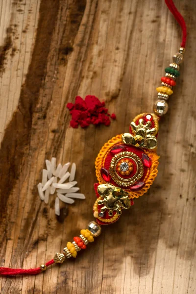 เทศกาลอินเดีย: พื้นหลังราชาบันดานกับ Rakhi, ข้าวธัญพืชและกุมมะที่สง่างาม วงข้อมืออินเดียแบบดั้งเดิมซึ่งเป็นสัญลักษณ์ของความรักระหว่างพี่น้องและพี่น้อง . — ภาพถ่ายสต็อก