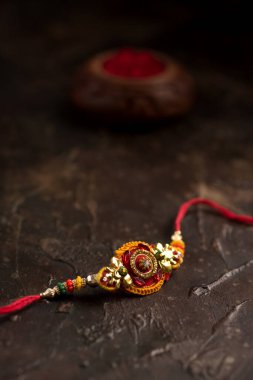 Raksha Bandhan 'ın arkaplanı zarif bir Rakhi, pirinç taneleri ve Kumkum. Geleneksel Hint bilekliği Kardeşler ve Kız Kardeşler arasındaki aşkın sembolüdür..