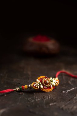 Raksha Bandhan 'ın arkaplanı zarif bir Rakhi, pirinç taneleri ve Kumkum. Geleneksel Hint bilekliği Kardeşler ve Kız Kardeşler arasındaki aşkın sembolüdür..