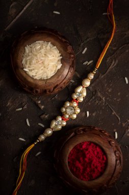 Raksha Bandhan 'ın arkaplanı zarif bir Rakhi, pirinç taneleri ve Kumkum. Geleneksel Hint bilekliği Kardeşler ve Kız Kardeşler arasındaki aşkın sembolüdür..