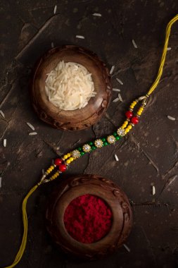 Raksha Bandhan 'ın arkaplanı zarif bir Rakhi, pirinç taneleri ve Kumkum. Geleneksel Hint bilekliği Kardeşler ve Kız Kardeşler arasındaki aşkın sembolüdür..