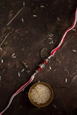 Raksha Bandhan 'ın arkaplanı zarif bir Rakhi, pirinç taneleri ve Kumkum. Geleneksel Hint bilekliği Kardeşler ve Kız Kardeşler arasındaki aşkın sembolüdür..