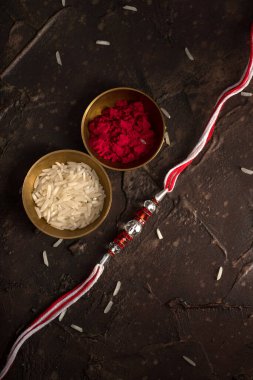 Raksha Bandhan 'ın arkaplanı zarif bir Rakhi, pirinç taneleri ve Kumkum. Geleneksel Hint bilekliği Kardeşler ve Kız Kardeşler arasındaki aşkın sembolüdür..
