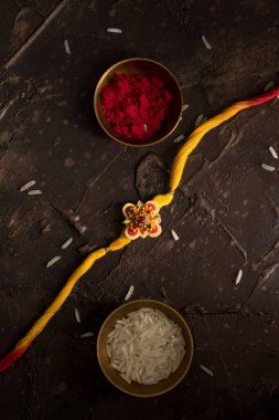 Raksha Bandhan 'ın arkaplanı zarif bir Rakhi, pirinç taneleri ve Kumkum. Geleneksel Hint bilekliği Kardeşler ve Kız Kardeşler arasındaki aşkın sembolüdür..