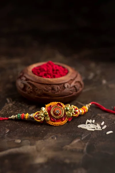 Raksha Bandhan 'ın arkaplanı zarif bir Rakhi, pirinç taneleri ve Kumkum. Geleneksel Hint bilekliği Kardeşler ve Kız Kardeşler arasındaki aşkın sembolüdür.. — Stok fotoğraf