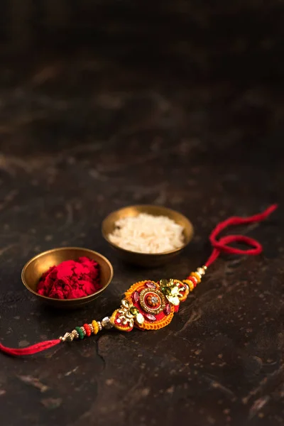 Raksha Bandhan background with an elegant Rakhi, Rice Grains and Kumkum. A traditional Indian wrist band which is a symbol of love between Brothers and Sisters. — Stock Photo, Image