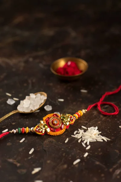 Raksha Bandhan 'ın arkaplanı zarif bir Rakhi, pirinç taneleri ve Kumkum. Geleneksel Hint bilekliği Kardeşler ve Kız Kardeşler arasındaki aşkın sembolüdür.. — Stok fotoğraf