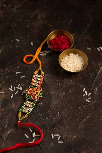 Raksha Bandhan background with an elegant Rakhi, Rice Grains and Kumkum. A traditional Indian wrist band which is a symbol of love between Brothers and Sisters. — Stock Photo, Image