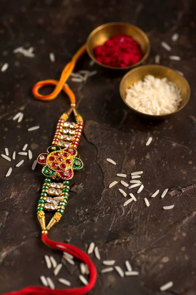 Raksha Bandhan fundo com um elegante Rakhi, grãos de arroz e Kumkum. Uma pulseira tradicional indiana que é um símbolo de amor entre irmãos e irmãs . — Fotografia de Stock