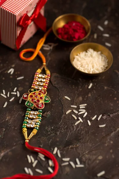 Raksha Bandhan φόντο με ένα κομψό Rakhi, Rice Grains και Kumkum. Ένα παραδοσιακό ινδικό περικάρπιο που είναι σύμβολο αγάπης μεταξύ αδελφών και αδελφών.. — Φωτογραφία Αρχείου