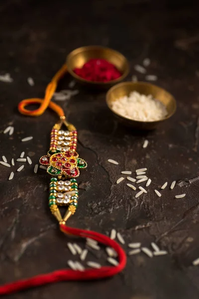 Raksha Bandhan background with an elegant Rakhi, Rice Grains and Kumkum. A traditional Indian wrist band which is a symbol of love between Brothers and Sisters. — Stock Photo, Image