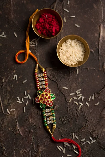 Raksha Bandhan 'ın arkaplanı zarif bir Rakhi, pirinç taneleri ve Kumkum. Geleneksel Hint bilekliği Kardeşler ve Kız Kardeşler arasındaki aşkın sembolüdür.. — Stok fotoğraf