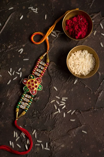 Raksha Bandhan background with an elegant Rakhi, Rice Grains and Kumkum. A traditional Indian wrist band which is a symbol of love between Brothers and Sisters. — Stock Photo, Image