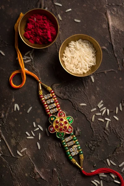 Raksha Bandhan background with an elegant Rakhi, Rice Grains and Kumkum. A traditional Indian wrist band which is a symbol of love between Brothers and Sisters. — Stock Photo, Image