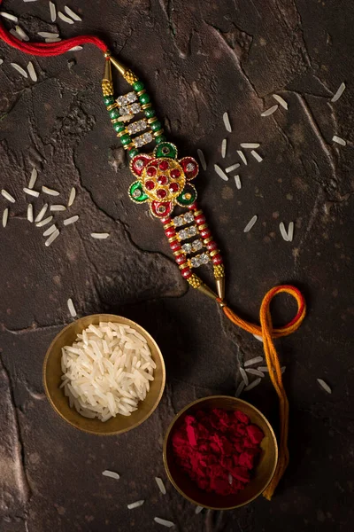 Raksha Bandhan background with an elegant Rakhi, Rice Grains and Kumkum. A traditional Indian wrist band which is a symbol of love between Brothers and Sisters. — Stock Photo, Image