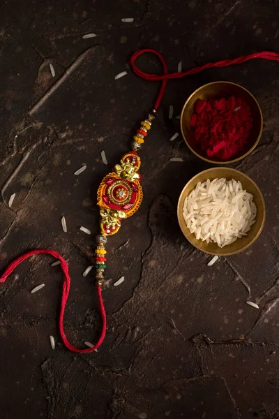 Raksha Bandhan Hintergrund mit einem eleganten Rakhi, Reiskörner und Kumkum. ein traditionelles indisches Armband, das ein Symbol der Liebe zwischen Brüdern und Schwestern ist. — Stockfoto