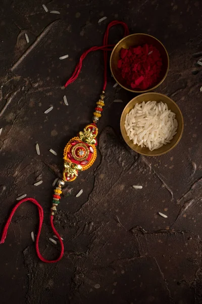 Raksha Bandhan background with an elegant Rakhi, Rice Grains and Kumkum. A traditional Indian wrist band which is a symbol of love between Brothers and Sisters. — Stock Photo, Image