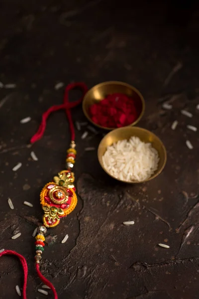 Raksha Bandhan background with an elegant Rakhi, Rice Grains and Kumkum. A traditional Indian wrist band which is a symbol of love between Brothers and Sisters. — Stock Photo, Image