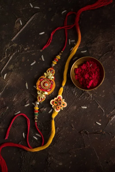 Raksha Bandhan background with an elegant Rakhi, Rice Grains and Kumkum. A traditional Indian wrist band which is a symbol of love between Brothers and Sisters. — Stock Photo, Image