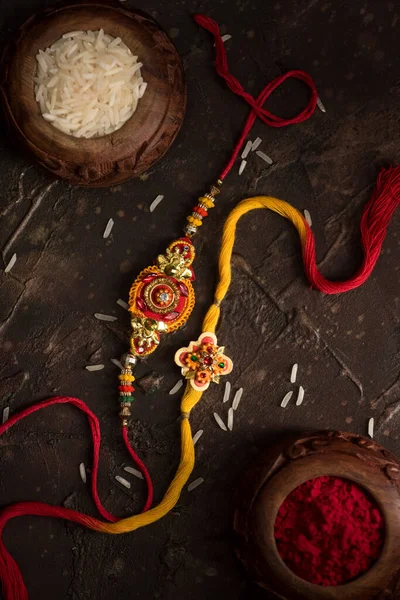 Raksha Bandhan fundal cu un elegant Rakhi, cereale de orez și Kumkum. O trupă tradițională indiană de încheietură a mâinii, care este un simbol al iubirii dintre frați și surori . — Fotografie, imagine de stoc