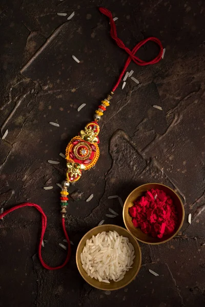 Raksha Bandhan fundal cu un elegant Rakhi, cereale de orez și Kumkum. O trupă tradițională indiană de încheietură a mâinii, care este un simbol al iubirii dintre frați și surori . — Fotografie, imagine de stoc