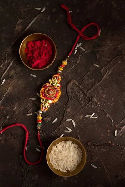 Raksha Bandhan 'ın arkaplanı zarif bir Rakhi, pirinç taneleri ve Kumkum. Geleneksel Hint bilekliği Kardeşler ve Kız Kardeşler arasındaki aşkın sembolüdür.. — Stok fotoğraf