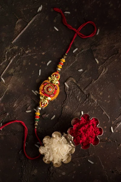 Raksha Bandhan Hintergrund mit einem eleganten Rakhi, Reiskörner und Kumkum. ein traditionelles indisches Armband, das ein Symbol der Liebe zwischen Brüdern und Schwestern ist. — Stockfoto