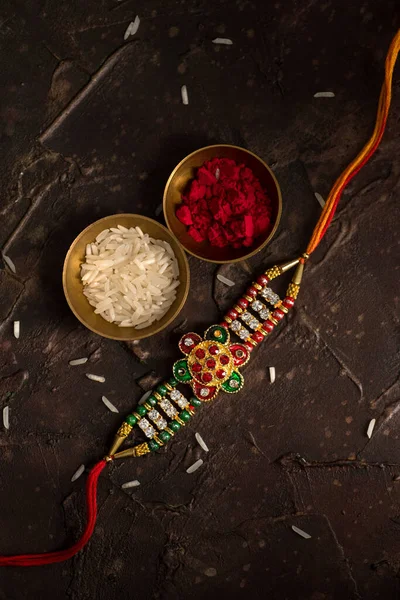 Raksha Bandhan background with an elegant Rakhi, Rice Grains and Kumkum. A traditional Indian wrist band which is a symbol of love between Brothers and Sisters. — Stock Photo, Image