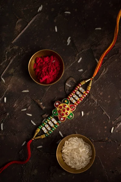 Raksha Bandhan 'ın arkaplanı zarif bir Rakhi, pirinç taneleri ve Kumkum. Geleneksel Hint bilekliği Kardeşler ve Kız Kardeşler arasındaki aşkın sembolüdür.. — Stok fotoğraf