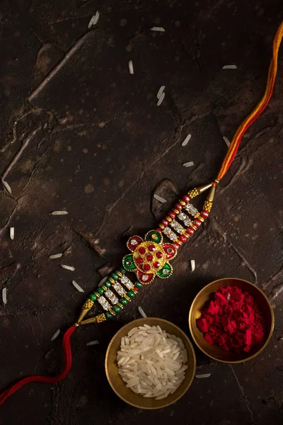 Raksha Bandhan background with an elegant Rakhi, Rice Grains and Kumkum. A traditional Indian wrist band which is a symbol of love between Brothers and Sisters. — Stock Photo, Image