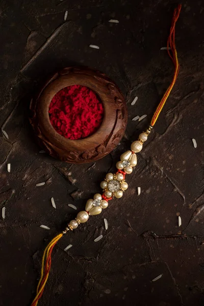 Raksha Bandhan background with an elegant Rakhi, Rice Grains and Kumkum. A traditional Indian wrist band which is a symbol of love between Brothers and Sisters. — Stock Photo, Image