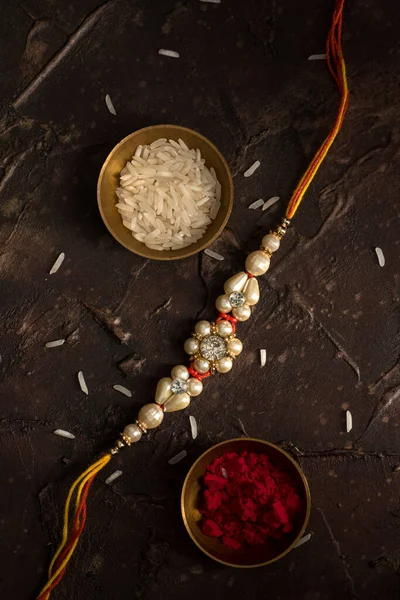 Raksha Bandhan background with an elegant Rakhi, Rice Grains and Kumkum. A traditional Indian wrist band which is a symbol of love between Brothers and Sisters. — Stock Photo, Image