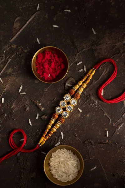 Raksha Bandhan fundal cu un elegant Rakhi, cereale de orez și Kumkum. O trupă tradițională indiană de încheietură a mâinii, care este un simbol al iubirii dintre frați și surori . — Fotografie, imagine de stoc