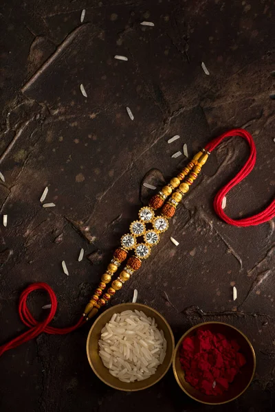 Raksha Bandhan background with an elegant Rakhi, Rice Grains and Kumkum. A traditional Indian wrist band which is a symbol of love between Brothers and Sisters. — Stock Photo, Image