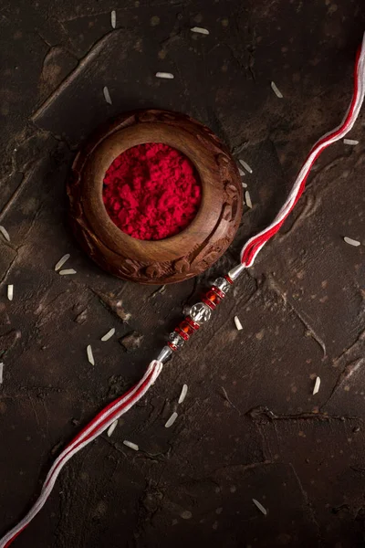 Raksha Bandhan background with an elegant Rakhi, Rice Grains and Kumkum. A traditional Indian wrist band which is a symbol of love between Brothers and Sisters. — Stock Photo, Image