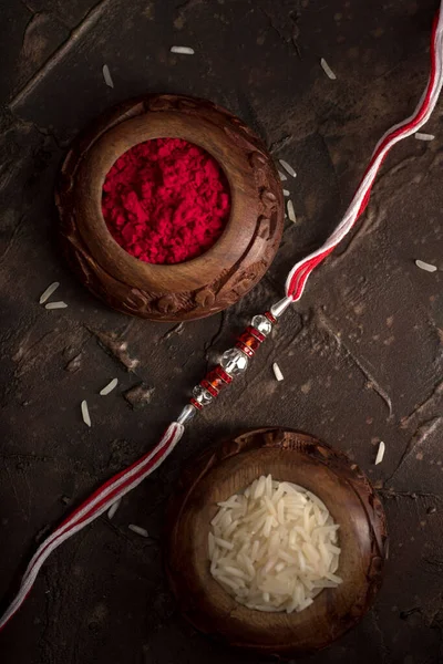 Raksha Bandhan background with an elegant Rakhi, Rice Grains and Kumkum. A traditional Indian wrist band which is a symbol of love between Brothers and Sisters. — Stock Photo, Image