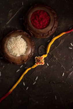 Raksha Bandhan 'ın arkaplanı zarif bir Rakhi, pirinç taneleri ve Kumkum. Geleneksel Hint bilekliği Kardeşler ve Kız Kardeşler arasındaki aşkın sembolüdür..