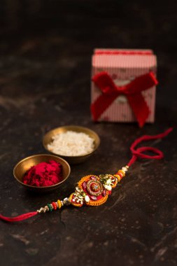 Raksha Bandhan zarif bir Rakhi, pirinç taneleri, Kumkum ve hediye kutusuna sahip. Geleneksel Hint bilekliği Kardeşler ve Kız Kardeşler arasındaki aşkın sembolüdür..