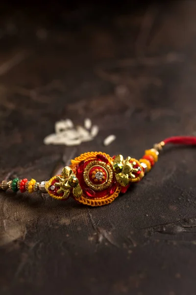 Raksha Bandhan-bakgrunn med en elegant Rakhi og spredd ris. Et tradisjonelt indisk armbånd som symboliserer kjærlighet mellom brødre og søstre . – stockfoto