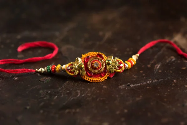 Fond Raksha Bandhan avec un élégant Rakhi et du riz éparpillé. Un bracelet traditionnel indien qui symbolise l'amour entre frères et sœurs . — Photo
