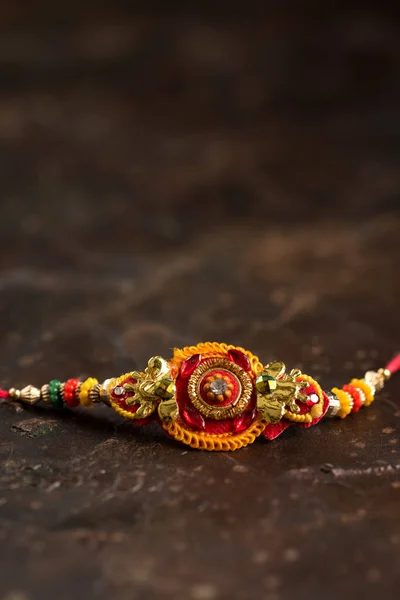 Raksha Bandhan-bakgrunn med en elegant Rakhi og spredd ris. Et tradisjonelt indisk armbånd som symboliserer kjærlighet mellom brødre og søstre . – stockfoto